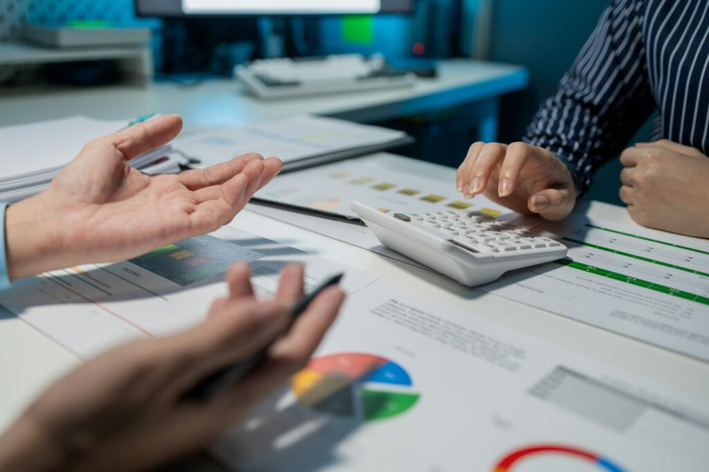 Personen analysieren Finanzdaten mit Taschenrechner und Diagrammen.